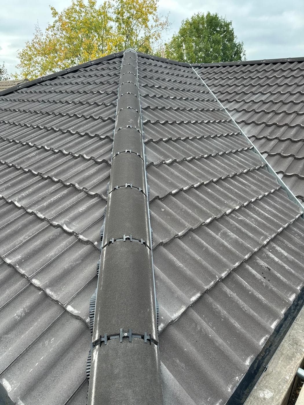 Looking up a hipped tiled roof to a dry ridge held by plastic clips