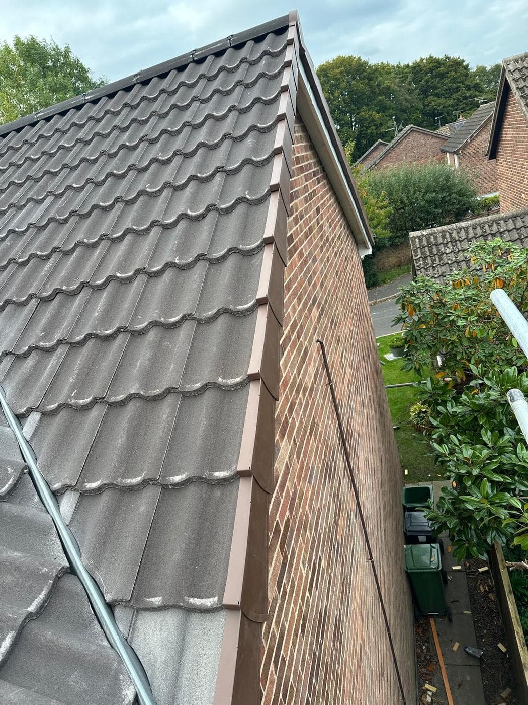 Grey pantiles running down to a brick gable finished with brown dry verge units