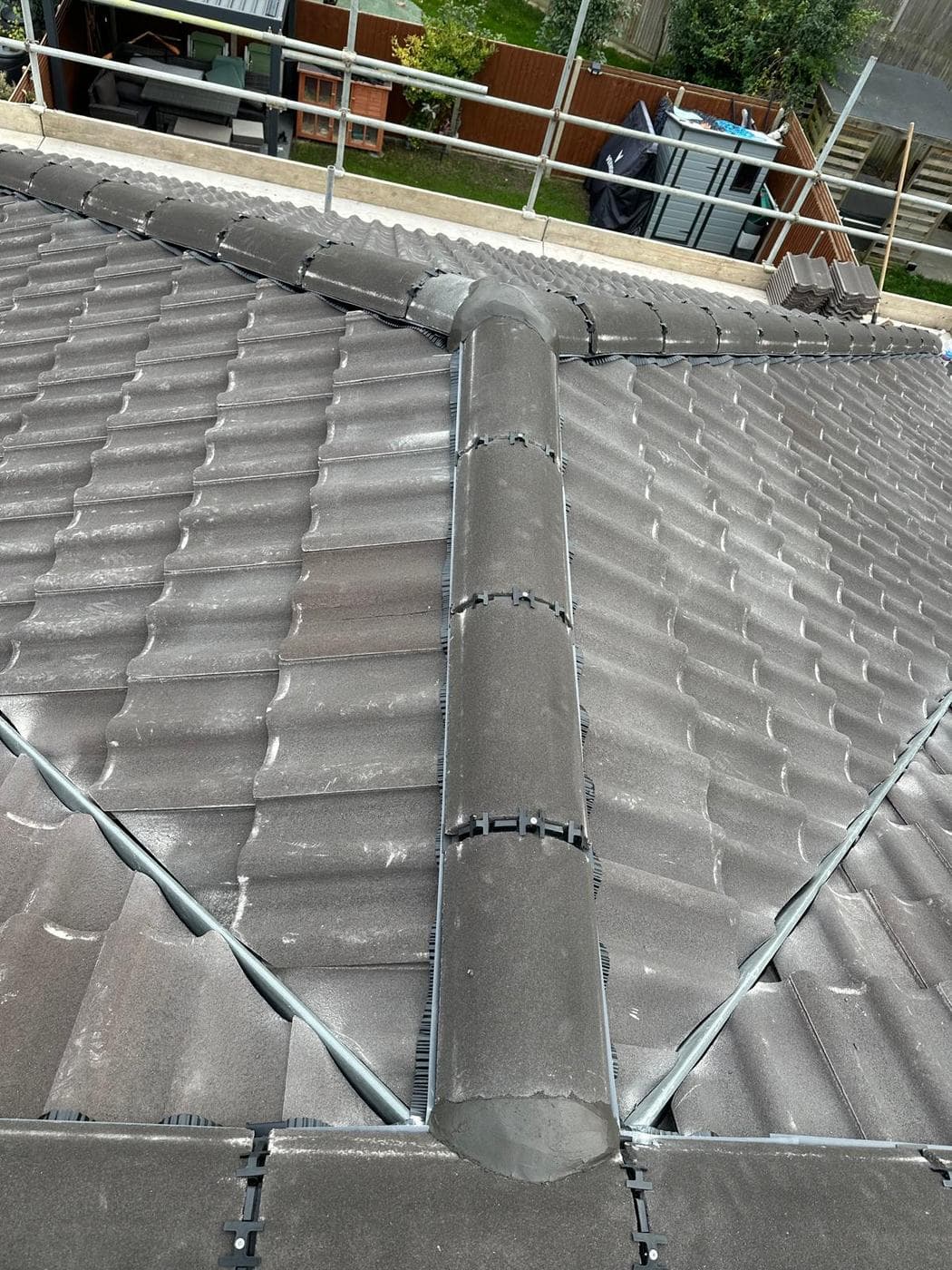 Overhead view of a finished hipped roof, spare tiles stacked on the scaffold boards