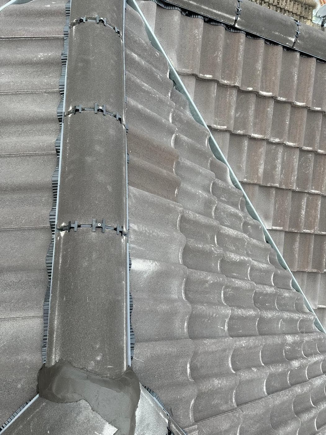 Close view of ridge and hip tiles, with mortar bedding where the two meet