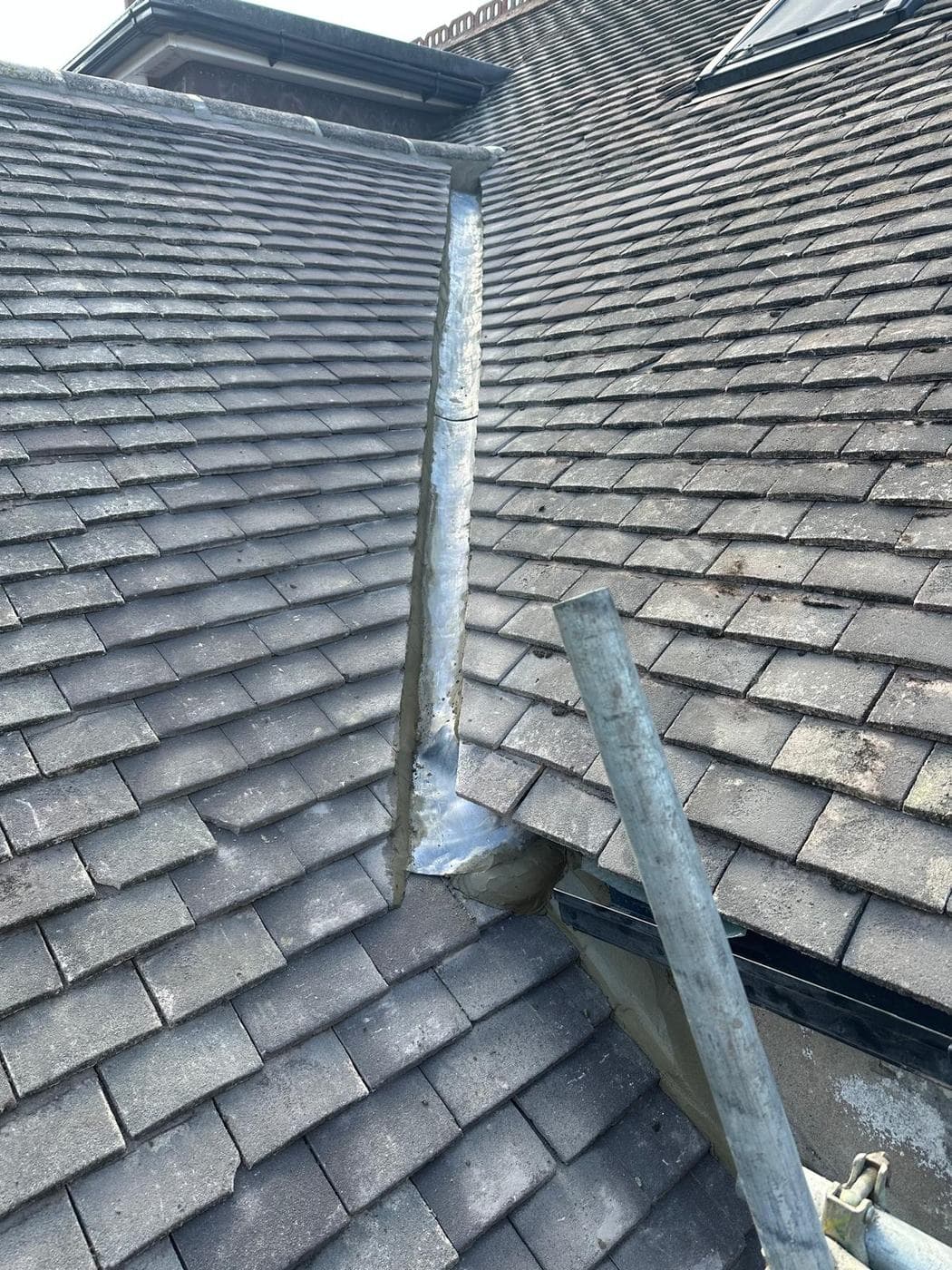 New lead valley running down from the ridge between two tiled roof slopes