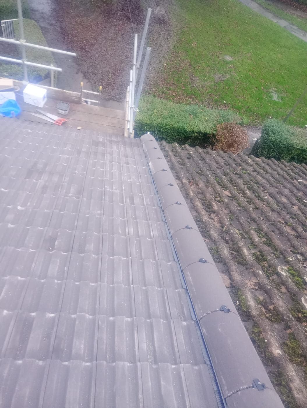 New dark tiles and a run of ridge tiles beside the neighbour's moss covered roof