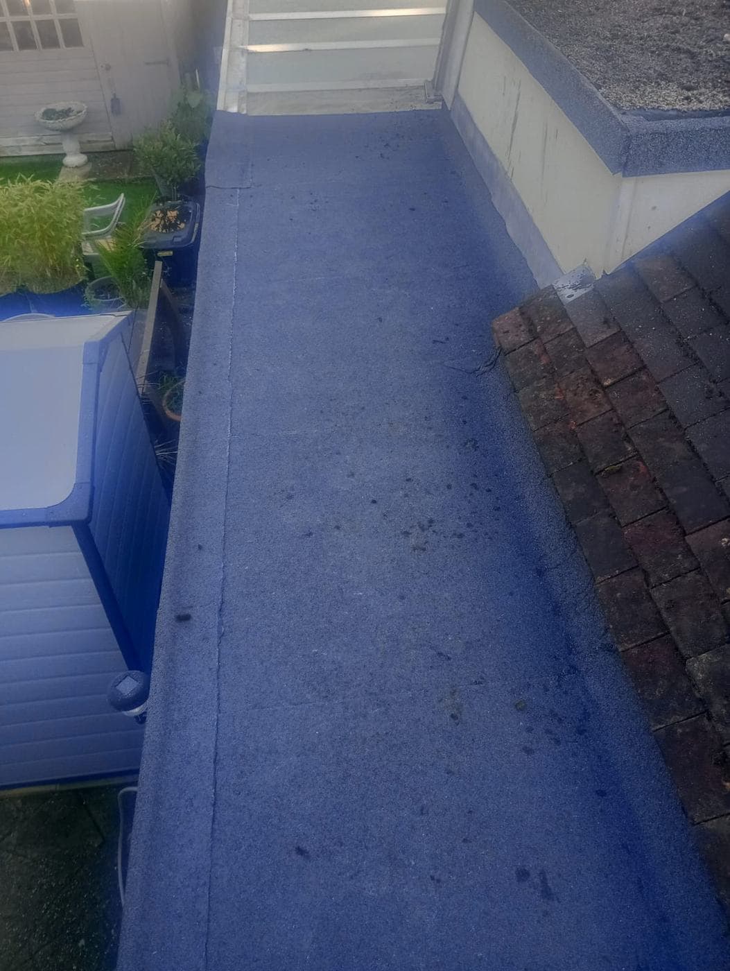 Finished grey mineral felt roof with a neat upstand, garden and shed below