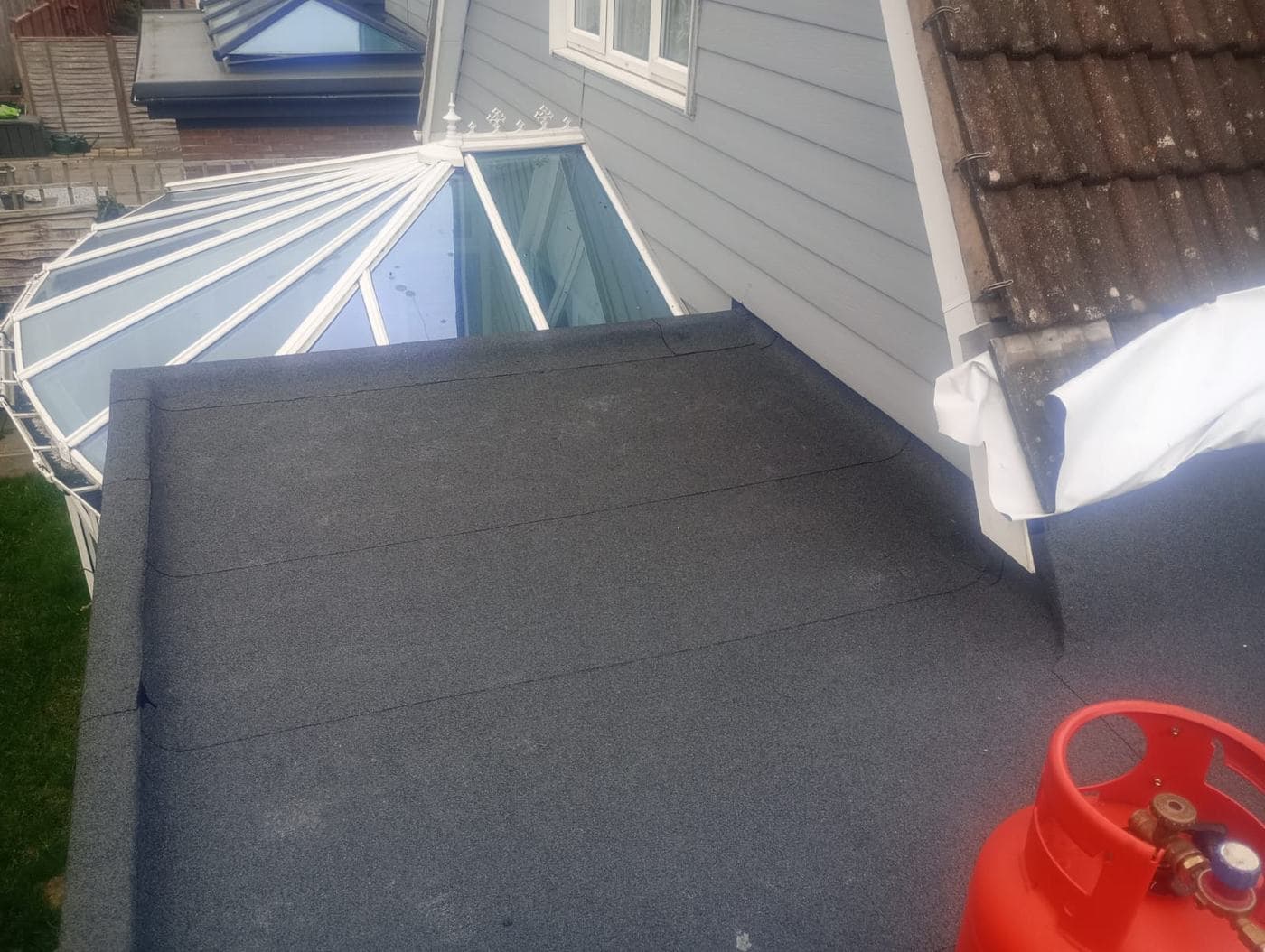 Newly finished felt roof meeting a glazed conservatory lantern and grey clad gable